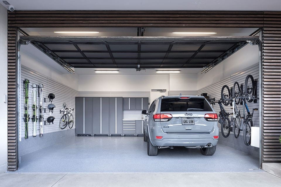 View into a newly built garage with a SUV parked and organized storage.
