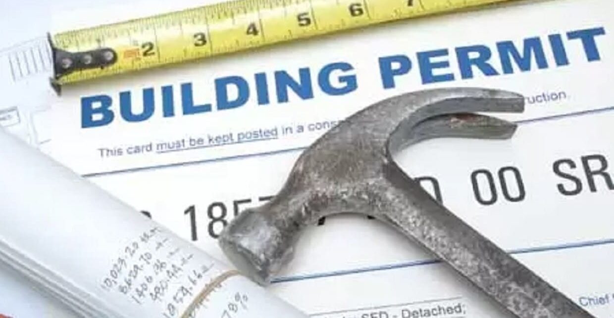 A building permit and drawings on a table with tools.